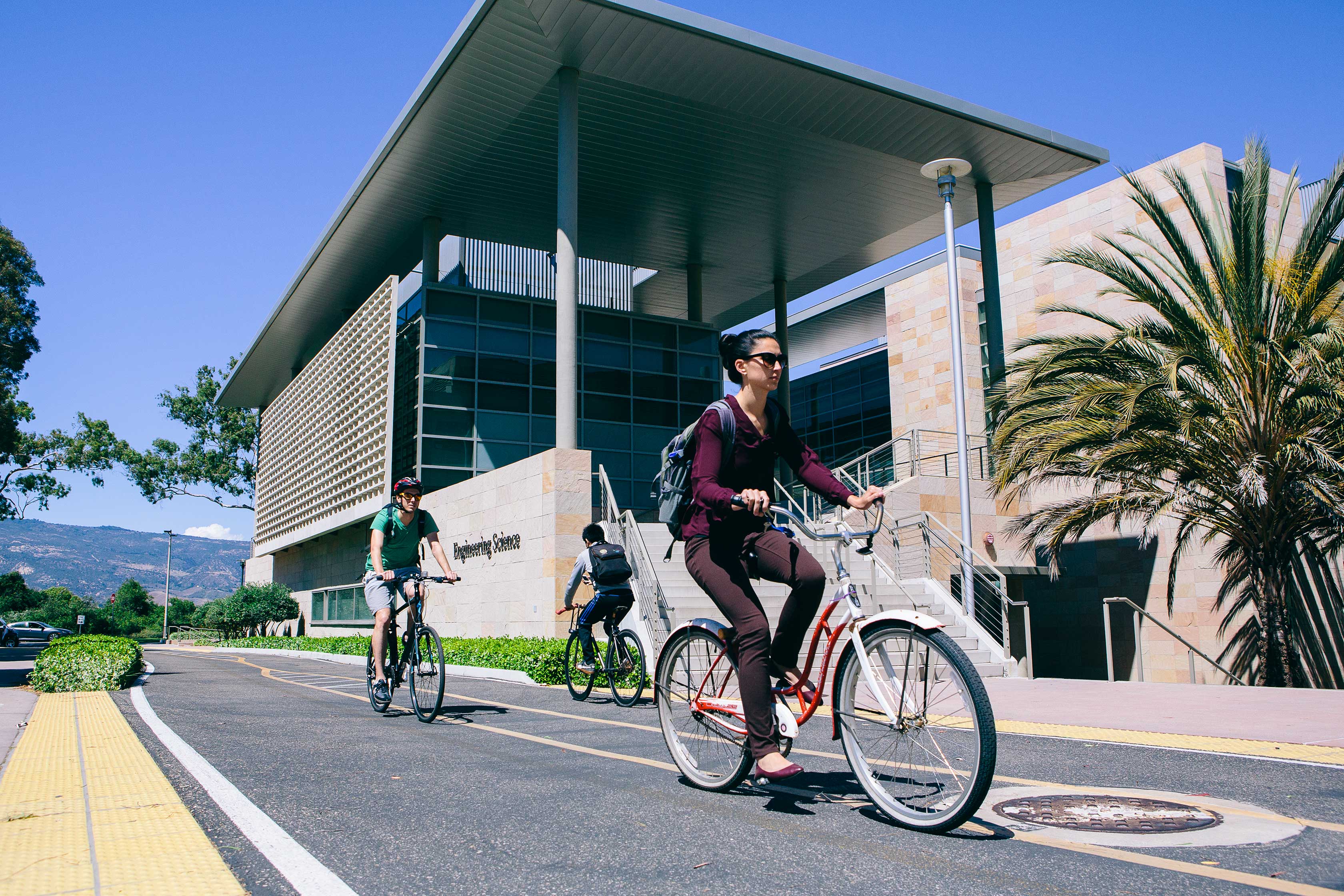 Young woman riding her bike passing by the engineering building