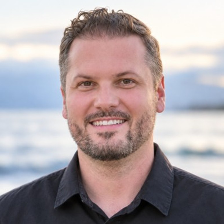 Photo headshot of CS Associate Professor Michael Beyeler in front of a body of water.