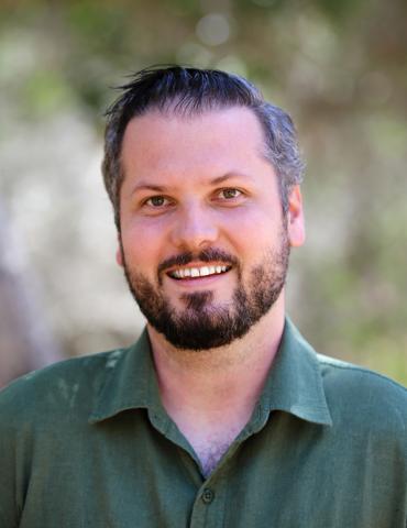 headshot of Michael, wearing green button up, smiling