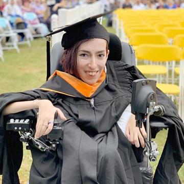 photo of Atieh, wearing a black graduation gown and hat, smiling